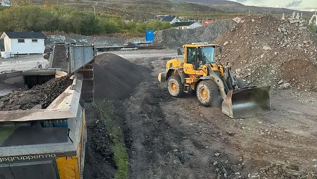 Hjullaster arbeider med masser på anleggsområde med grushauger