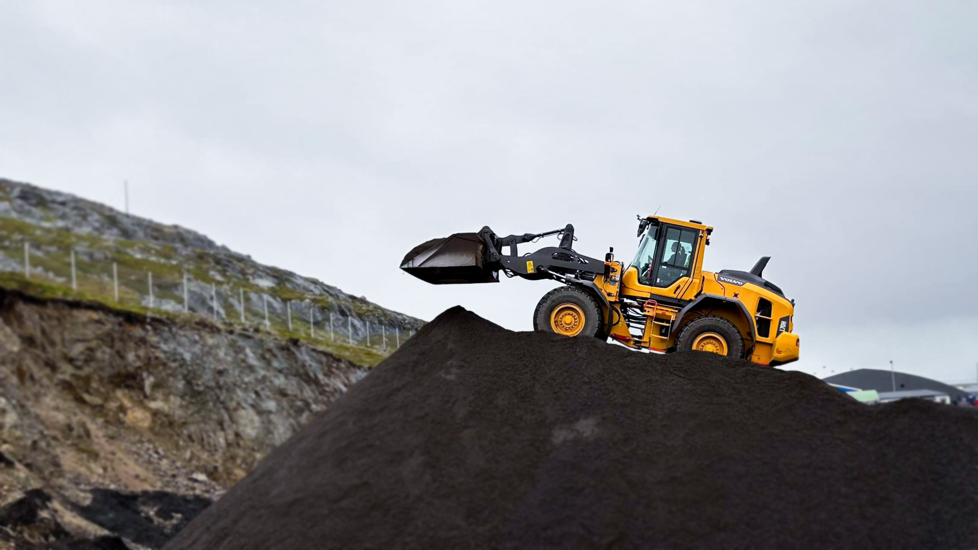 Hjullaster arbeider på toppen av stor grushaug i pukkverk
