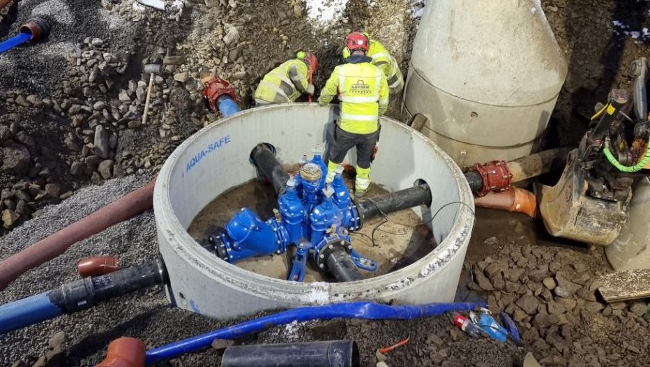 Montering av vannkum og rør med arbeidere i vinterforhold