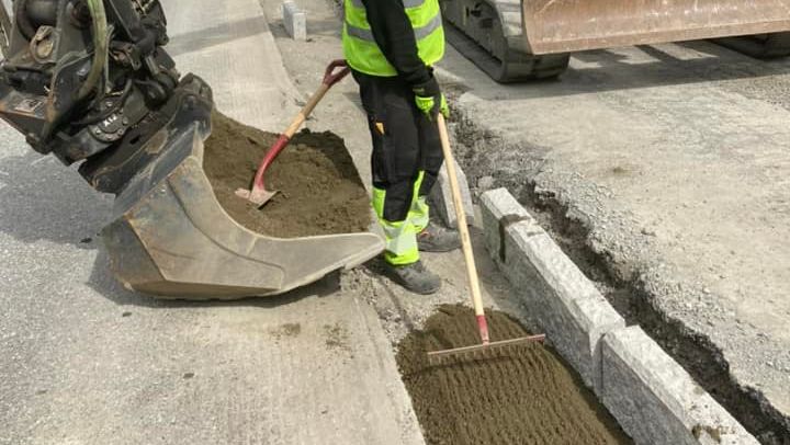 Arbeider raker fylmateriale i grop for avretting av betong